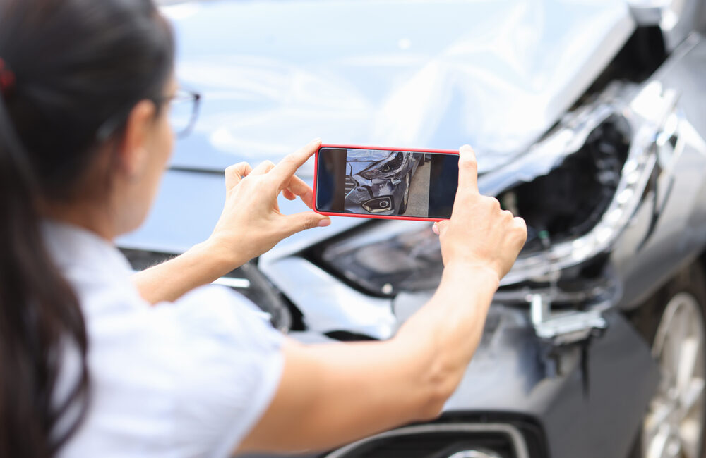 woman taking photos of car after accident