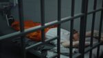 man laying in a jail cell